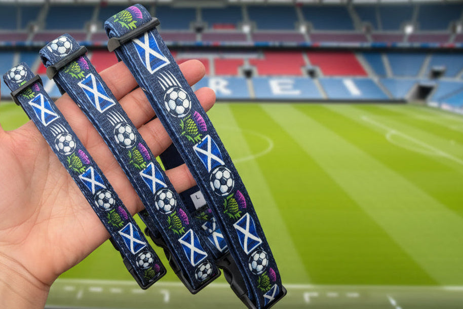 Three dog collars with Scottish flag and soccer ball pattern held in a hand, outdoor background