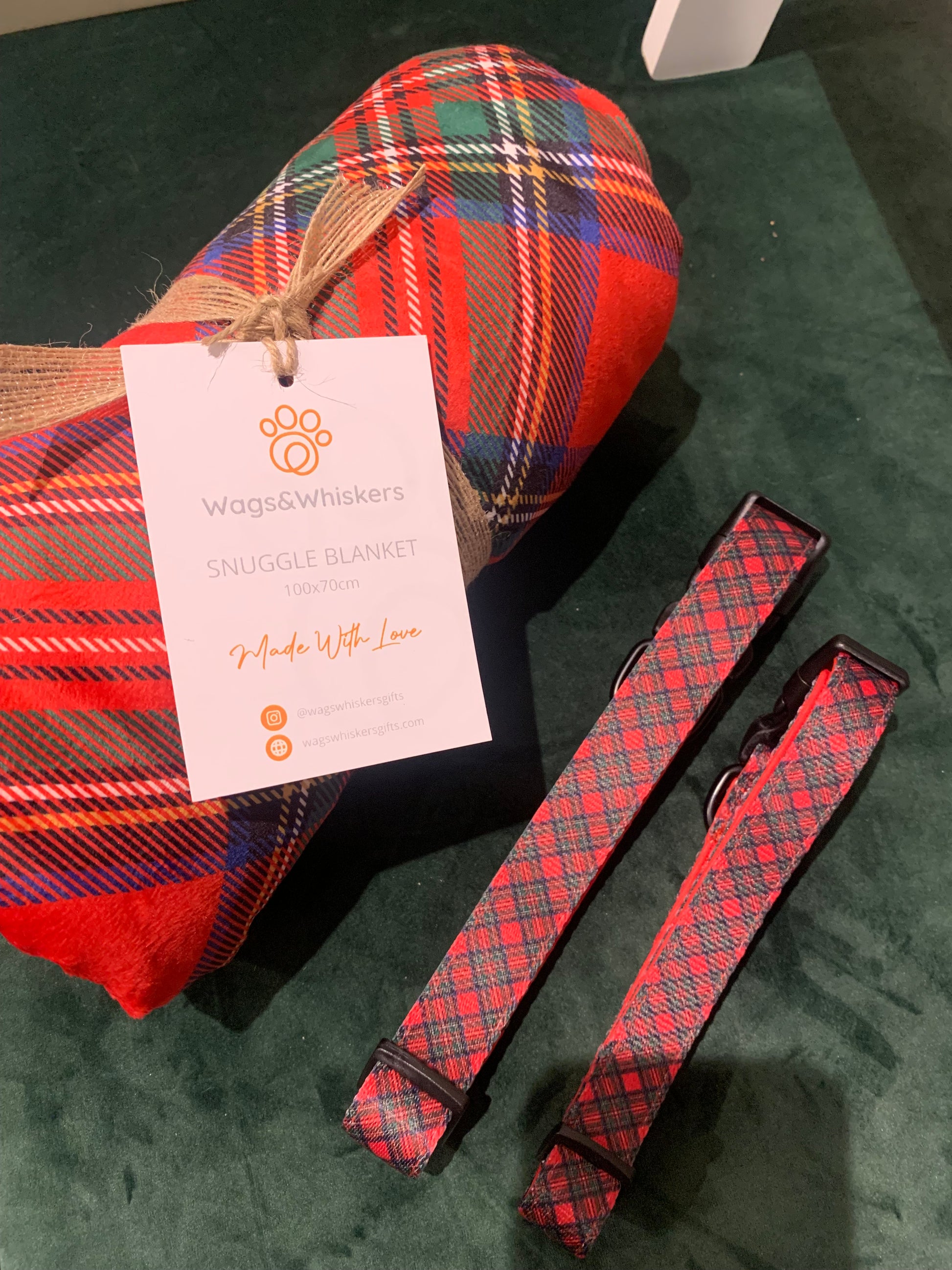Red plaid dog collar and leash set on a green surface with a card in the foreground.