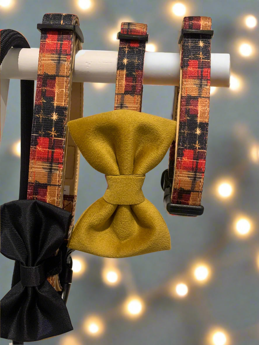 Plaid dog collars and bow ties on a white stand against a neutral background